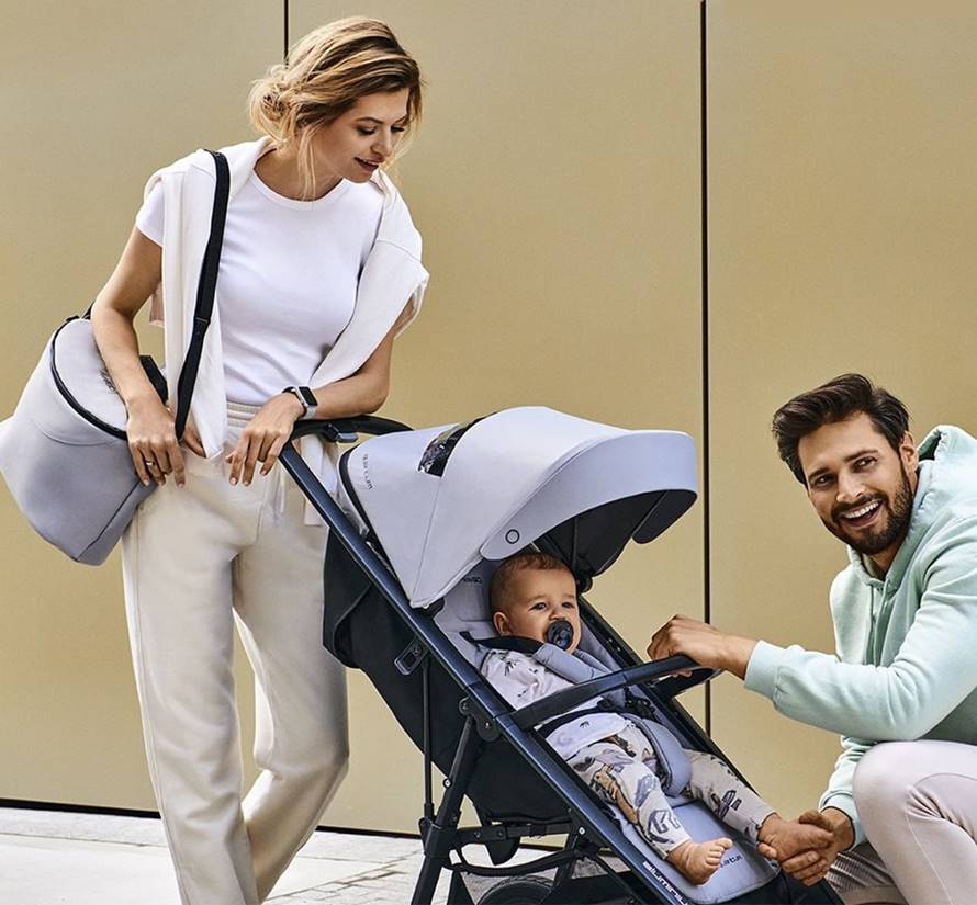 Rodzice nachylają się nad dzieckiem w spacerówce w pozycji półleżącej – idealne rozwiązanie przejściowe z gondoli